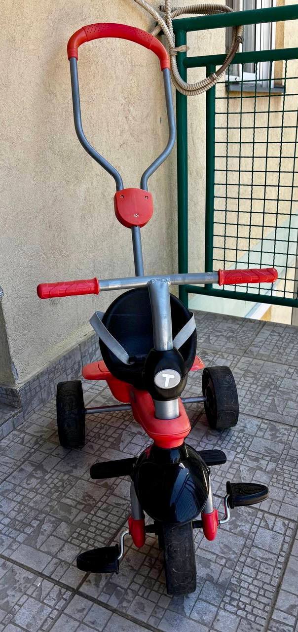 - Детский трёхколёсный трицикл SmarTrike Трёхколёсный трицикл SmarTrike с длинной родительской ручкой, ремнями безопасности, крутящими педалями и подставками для ног. — фото